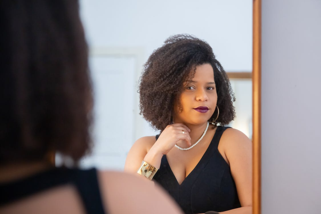 Woman looking in a mirror while learning how to build confidence from scratch through self-trust.