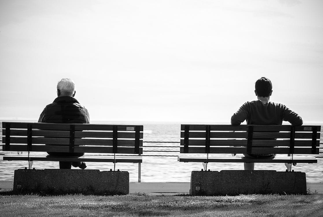 Two people sitting apart on benches showing why friendships fade as life and priorities change.
