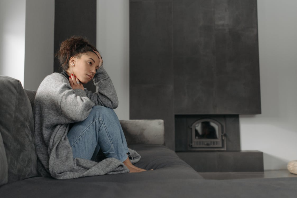 Thoughtful person sitting alone on a couch while feeling behind in life and reflecting on personal progress.
