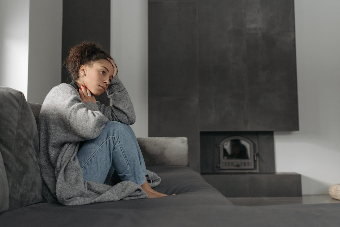 Thoughtful person sitting alone on a couch while feeling behind in life and reflecting on personal progress.