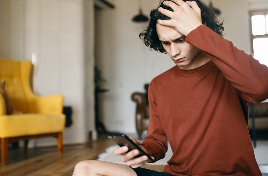 Anxious person checking phone while wondering why do I care what others think.