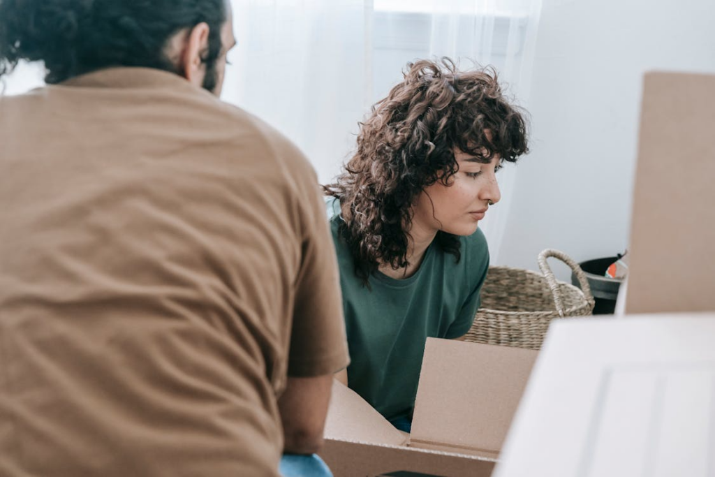 Person hesitating while packing boxes showing why do people resist change during life transitions.