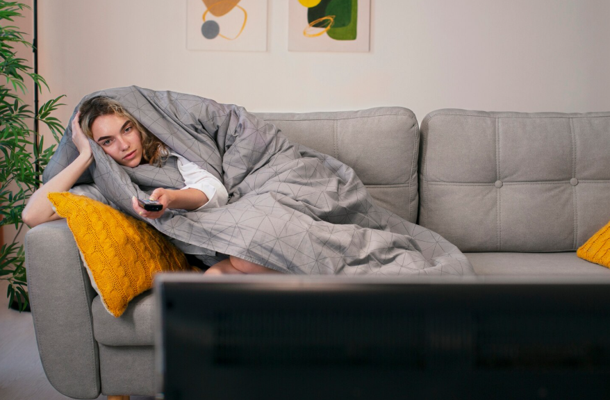 Person relaxing on a couch showing why do people rewatch shows for comfort and stress relief.