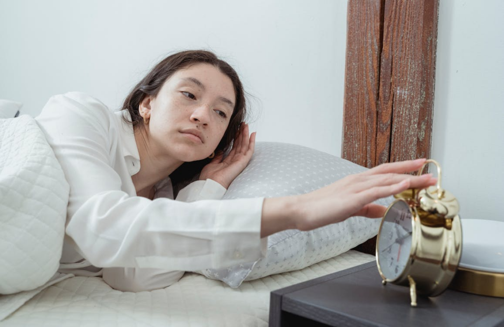 Person reaching for an alarm clock after waking up before alarm sounds in the morning.
