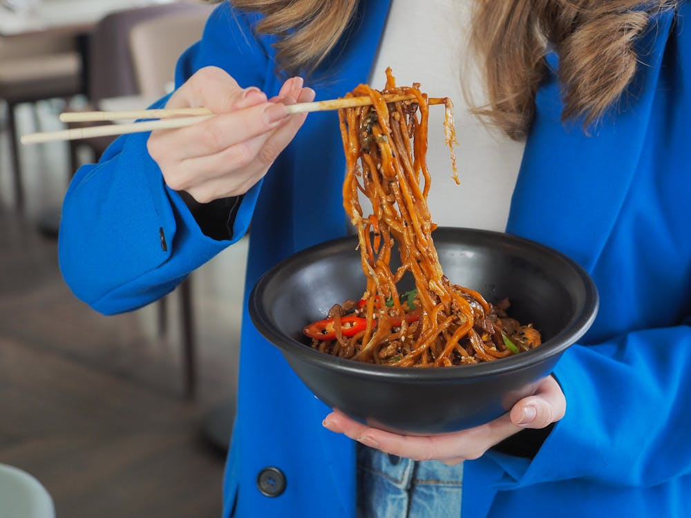 Person eating spicy noodles showing why do people like spicy food for heat and enjoyment.
