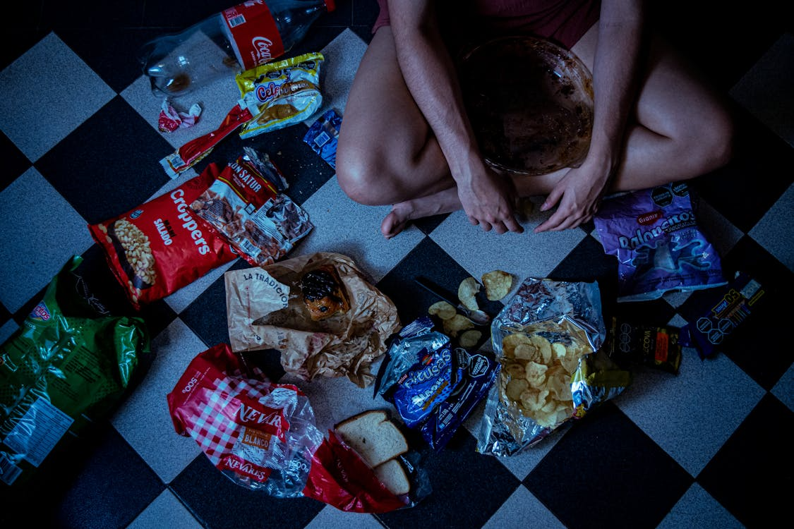 person surrounded by snacks at night showing why we crave junk food before bed