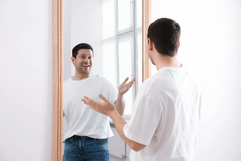 person talking to himself in a mirror illustrating why we talk to ourselves