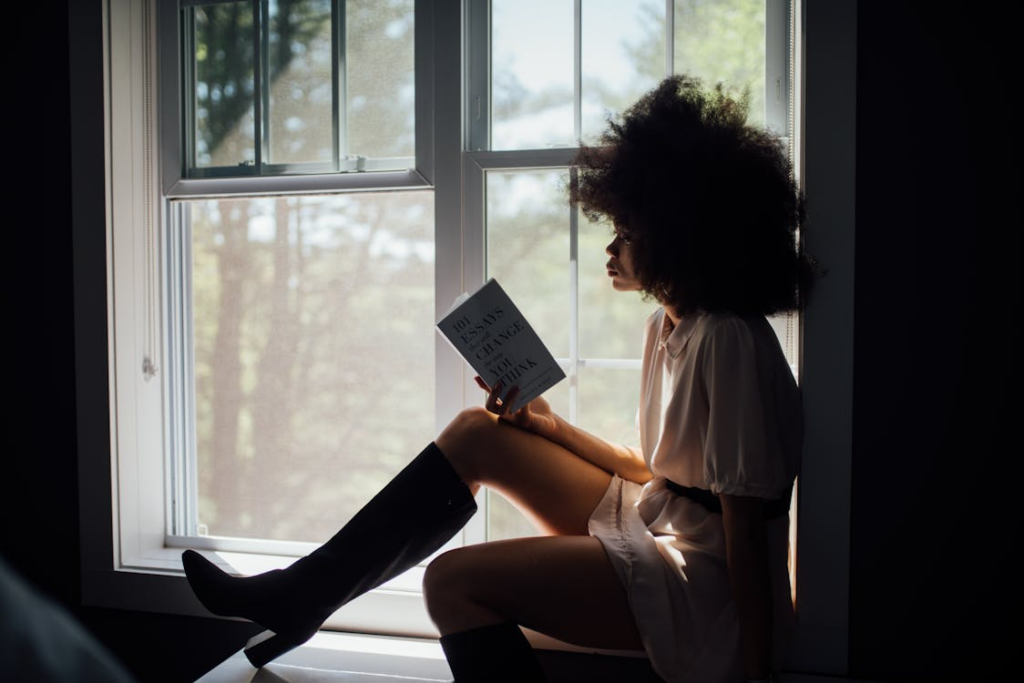 Person reading alone by a window while reflecting on is it bad to not like socializing.