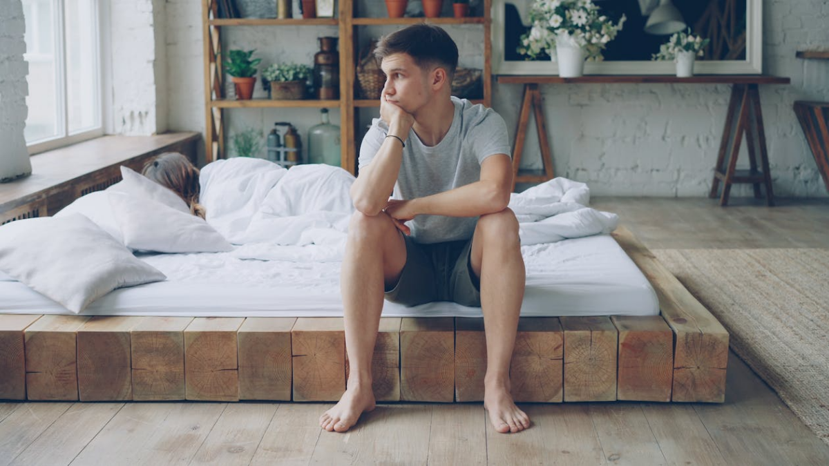Thoughtful man sitting on a bed wondering what to do with my life and how to find direction.